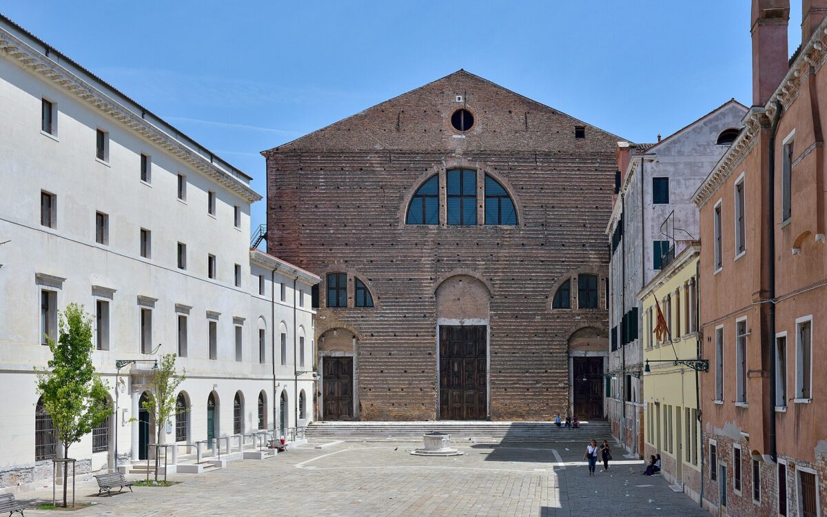 Veduta esterna della Chiesa di San Lorenzo a Venezia affacciata su un canale, sotto un cielo luminoso.