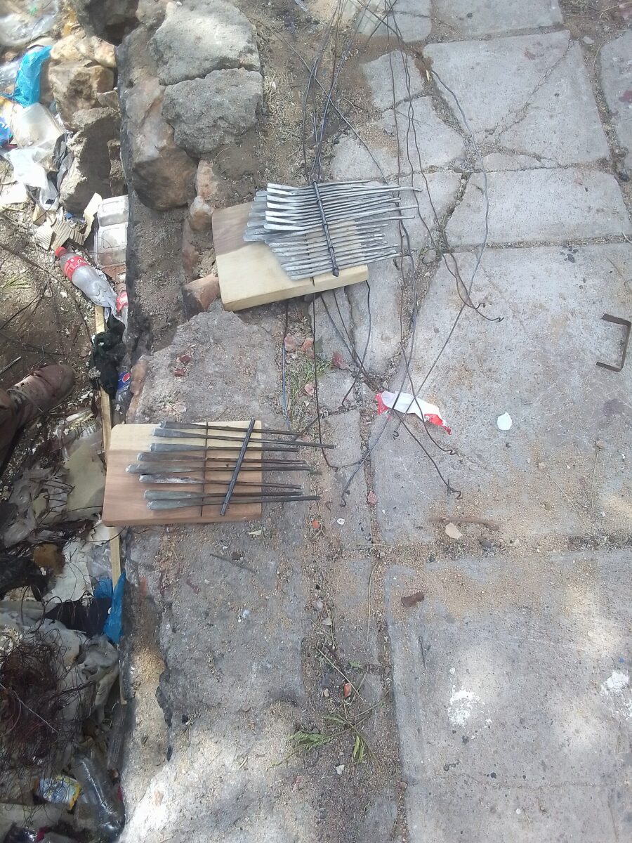 Mani sistemano lamelle metalliche parallele su una tavola di legno durante la costruzione di una mbira.
